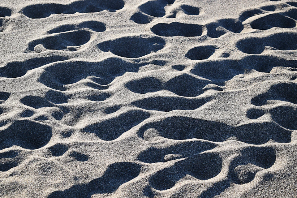 Close-up view of sandy beach with scattered footprints on light brown sand surface