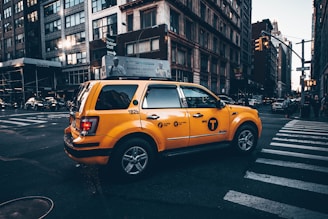 A taxi driving through a busy urban intersection during daytime.