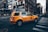 A taxi driving through a busy city street during the day.