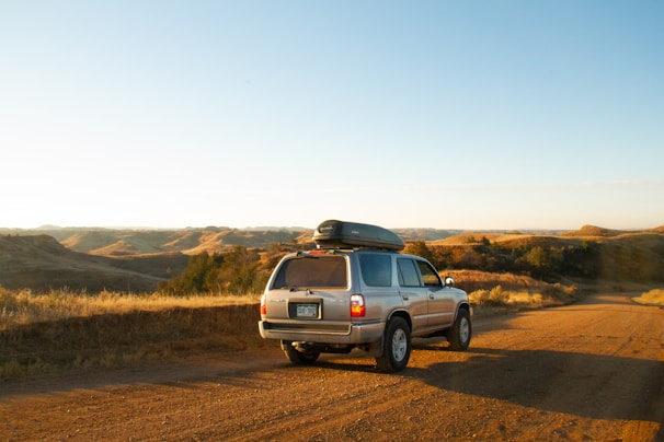 A family happily loading their rental car at a sunny roadside rest stop.