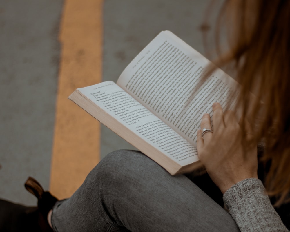woman wearing gray long-sleeved shirt reading book