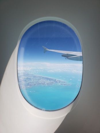plane wing on air above body of water during daytime
