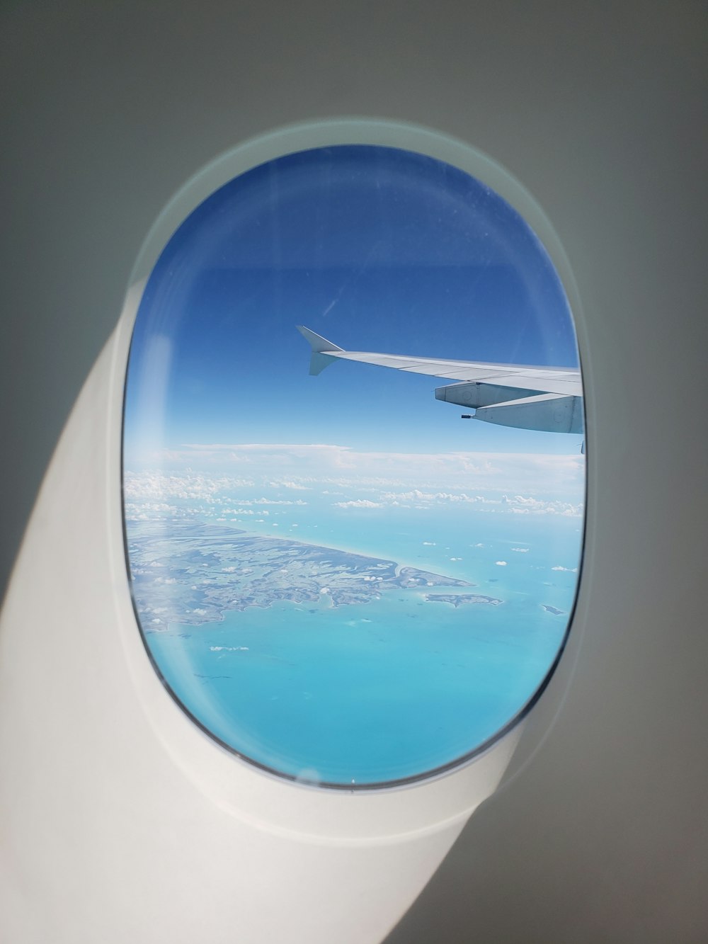 plane wing on air above body of water during daytime