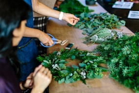 person holding scissors and leaf wreath