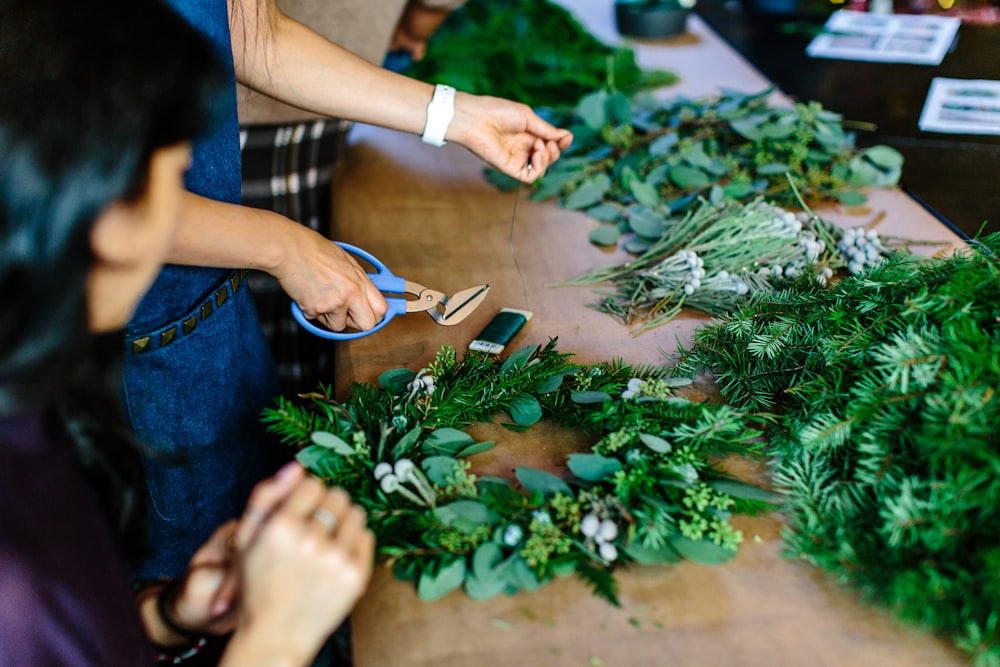person holding scissors and leaf wreath