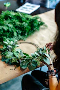 Close-up of hands weaving a traditional wreath from fresh herbs.