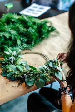 Close-up of hands weaving a traditional wreath from fresh herbs.