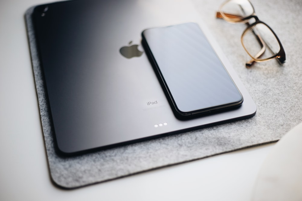 black iPad beside eyeglasses