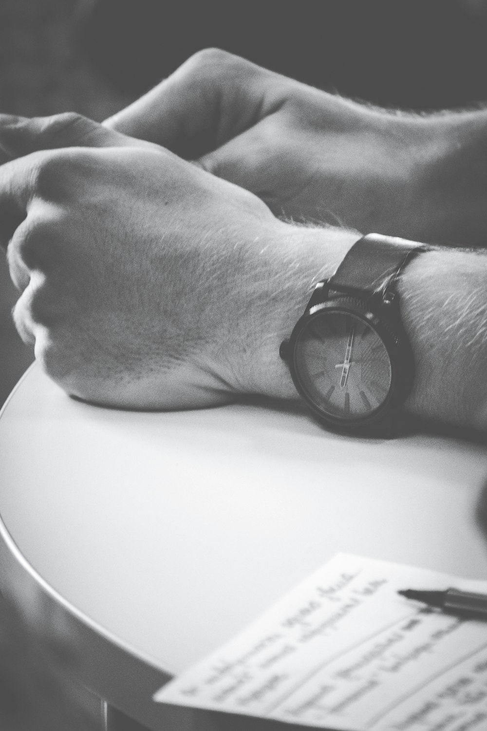 person wearing black watch with hand on table