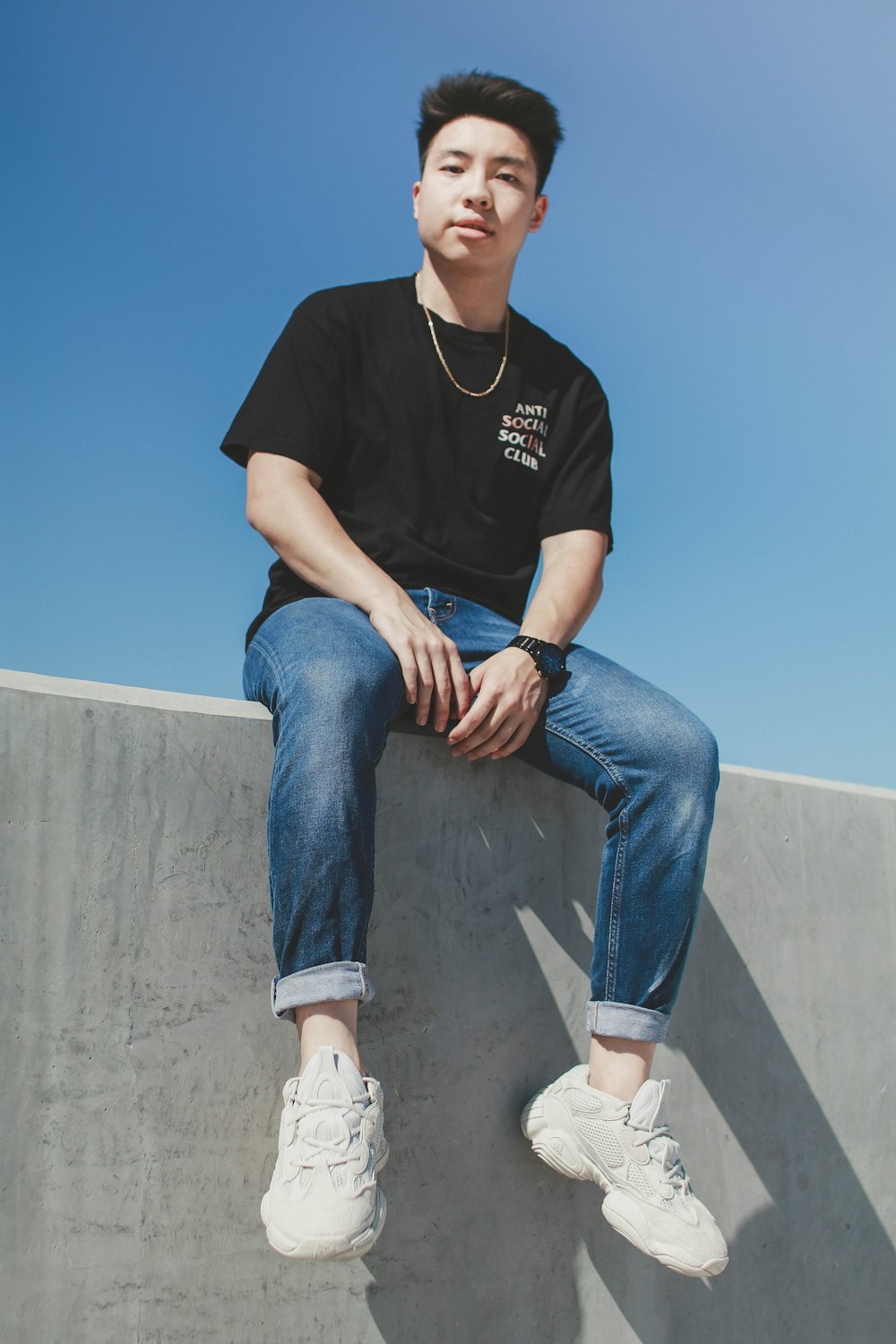 man sitting on concrete pavement under clear blue sky during daytime