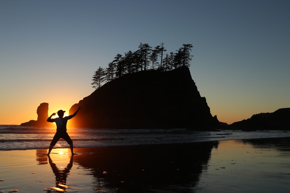 silhouette of man standing near body of water