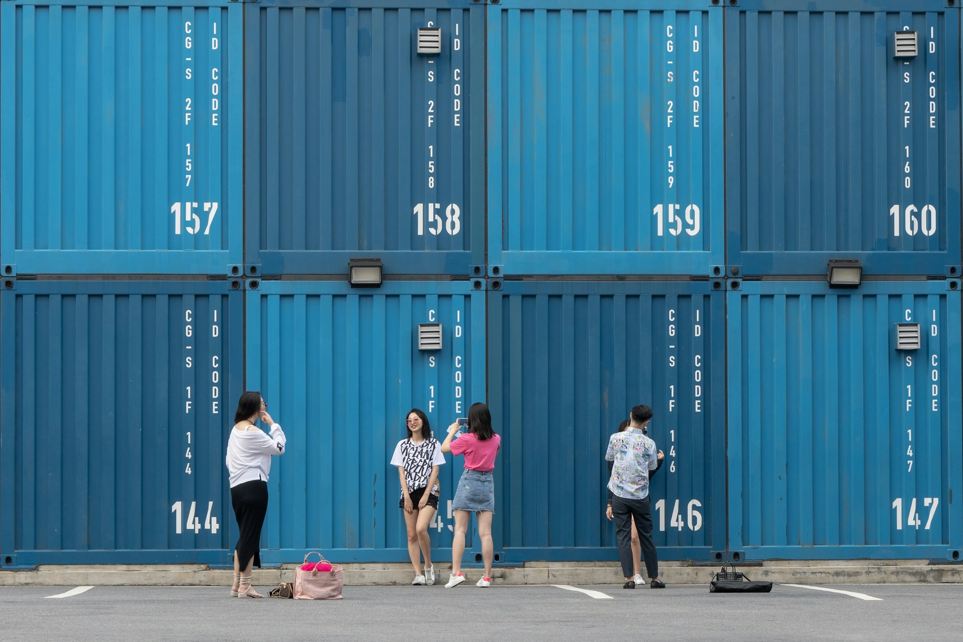 five women and man standing near shipping containers during daytime