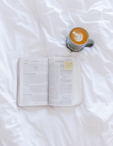 opened book beside cappuccino