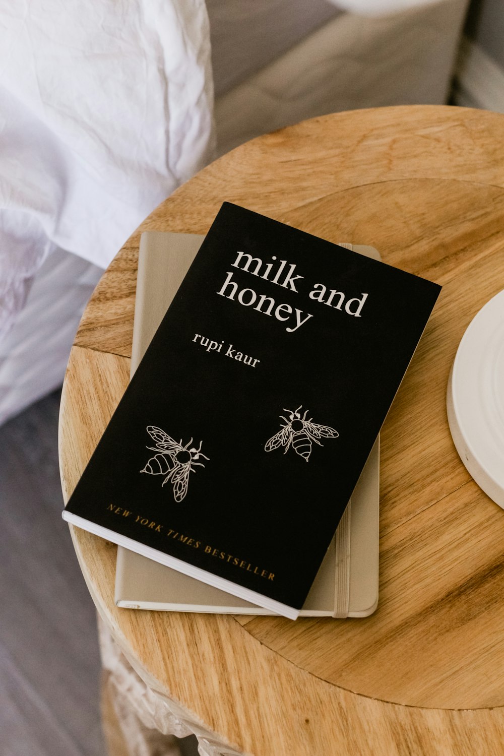 Livro Leite e Mel de Rupi Kaur na mesa lateral