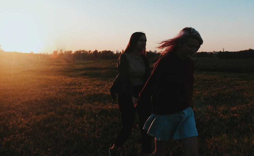 two women walking on grass field