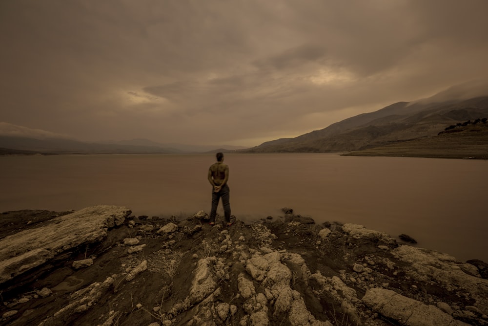 man standing at the edge of a rock island