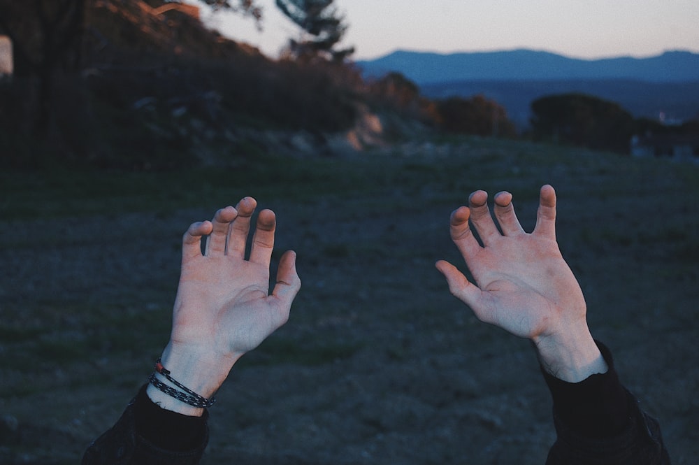 person raising hands above during golden hour