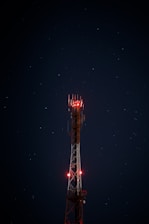white and red metal satellite tower during nighttime