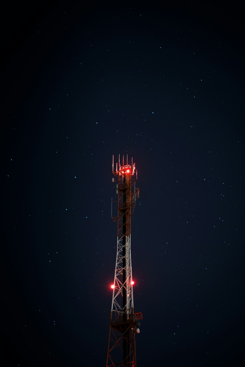 torre satélite de metal branco e vermelho durante a noite