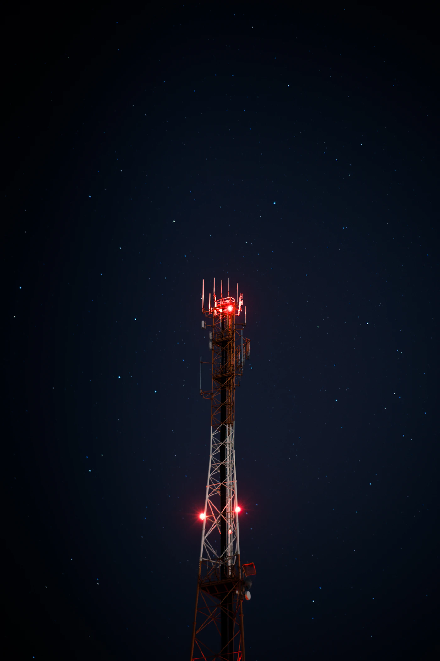 Telecom-antenne met rode lichten onder een sterrenhemel