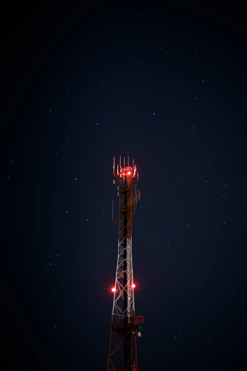 Red and white telecom tower at night