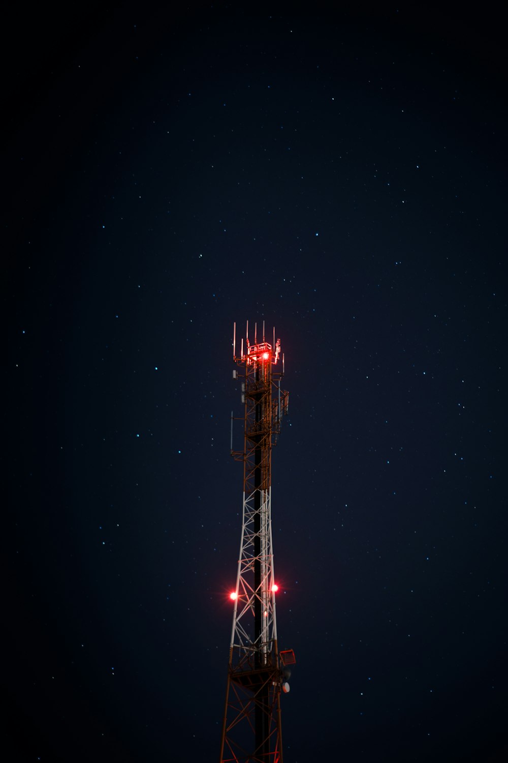 white and red metal satellite tower during nighttime