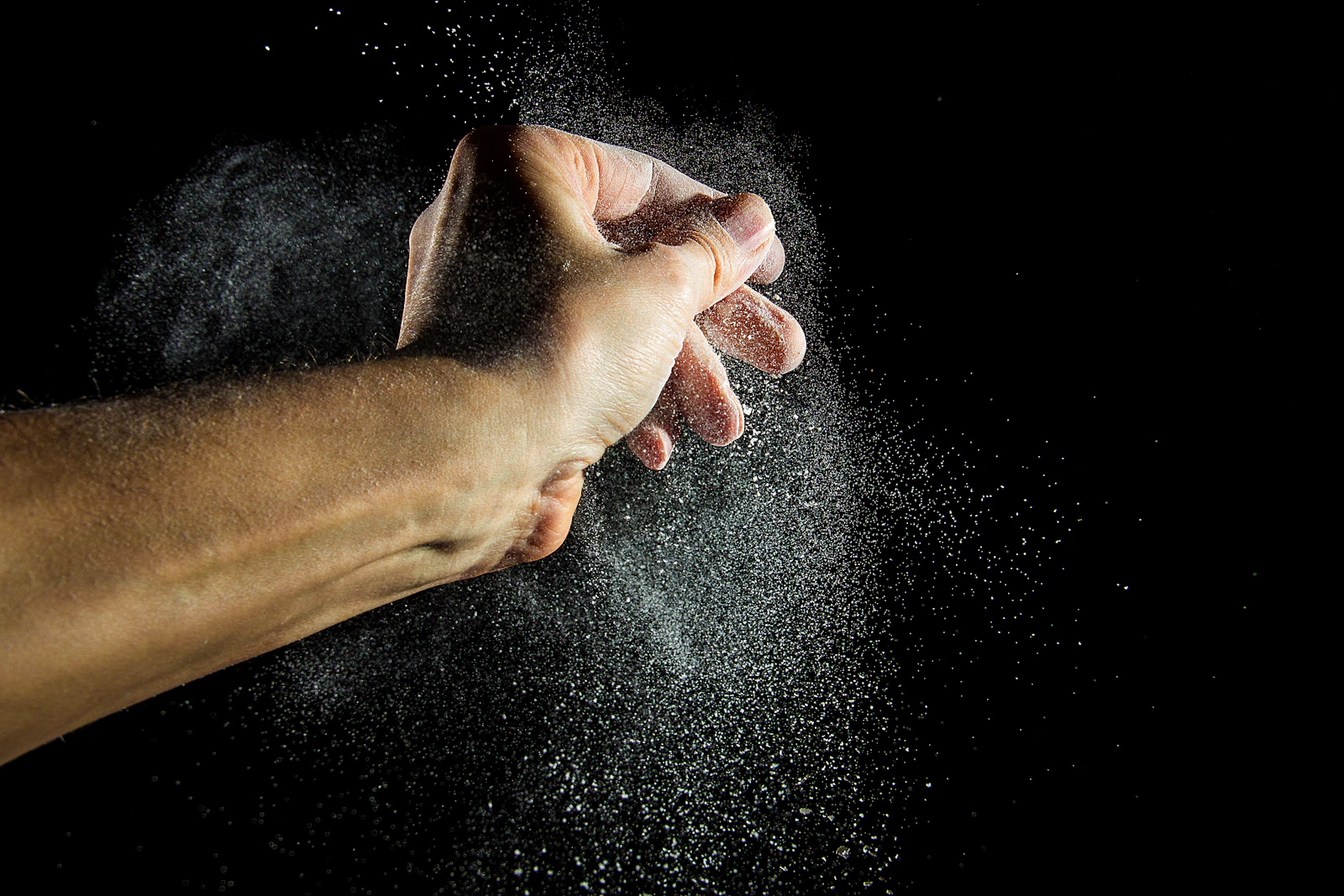 A lifter clapping chalk off their palms between sets