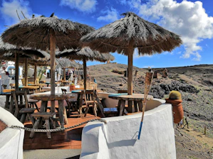 A rustic wooden table set outside with plates of colorful southwestern dishes and fresh coffee, framed by red rock cliffs in the background.