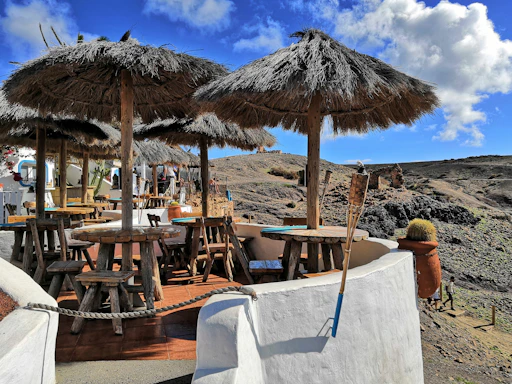 A rustic wooden table set outside with plates of colorful southwestern dishes and fresh coffee, framed by red rock cliffs in the background.