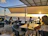 Outdoor seating overlooking the Hudson River with patrons enjoying cocktails.