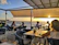 Outdoor seating overlooking the Hudson River with patrons enjoying cocktails.