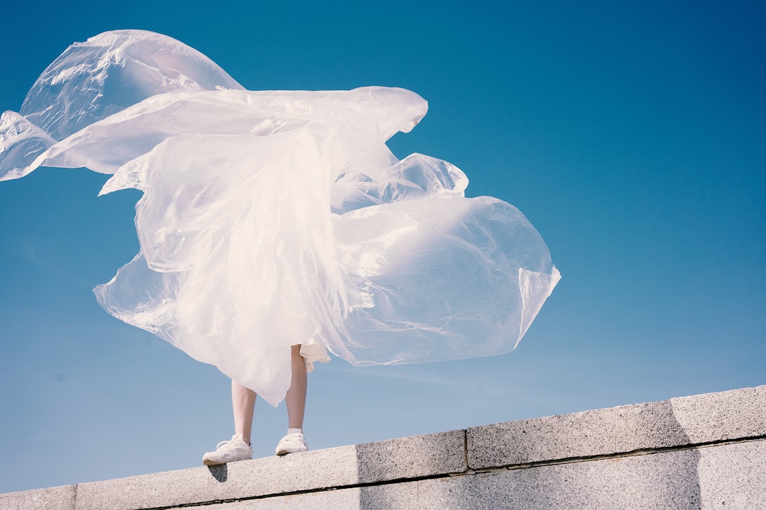 person holding plastic while standing on wall, sky girl