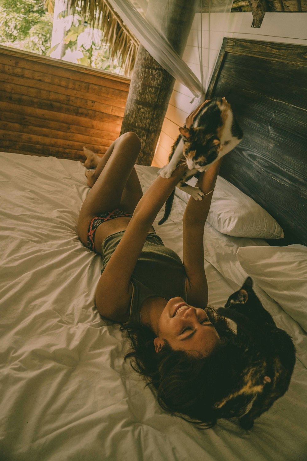woman lying on bed while holding a cat