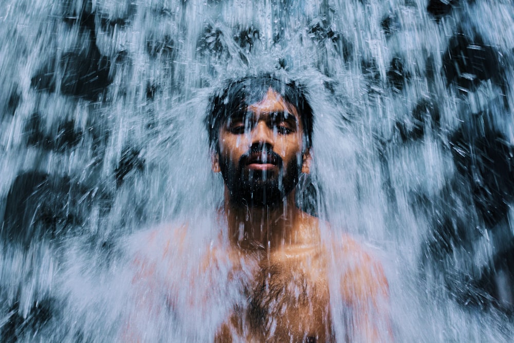 man sitting in front of waterfalls