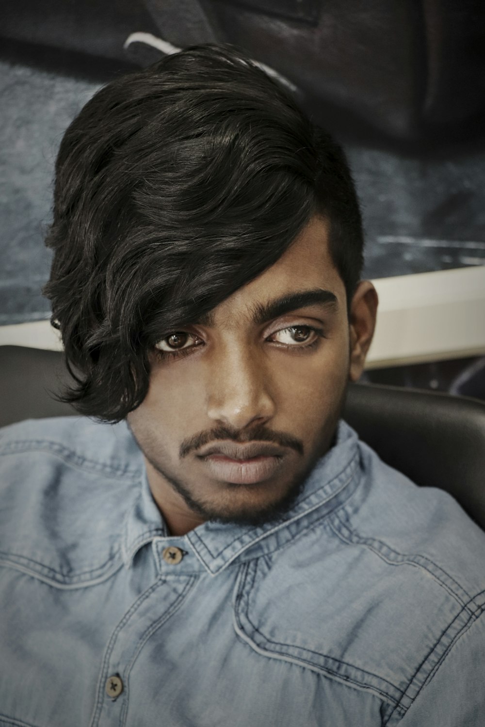 man frowning while sitting on black backrest