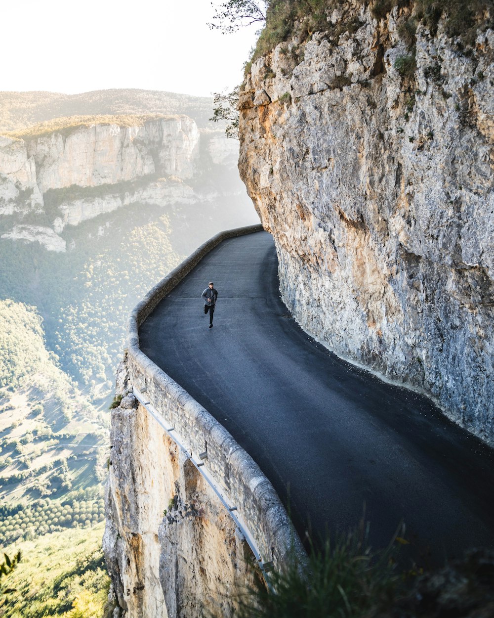 man jogging at the road of a rocky mountain during day