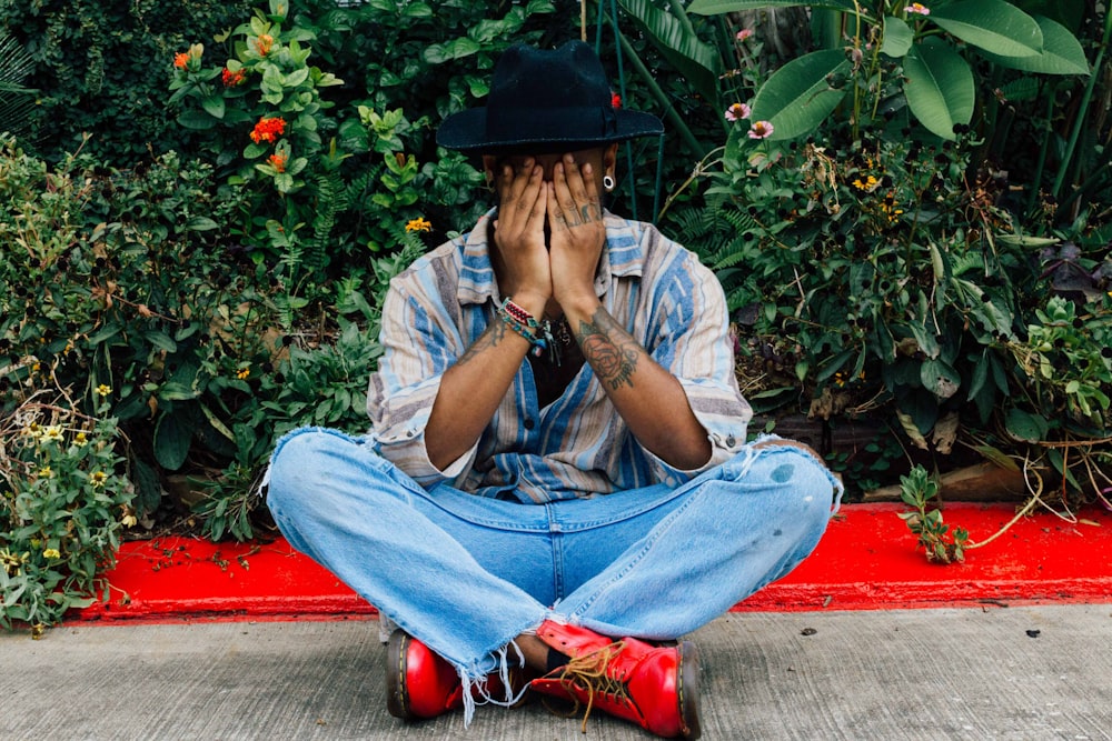 man sitting on pavement covering his face