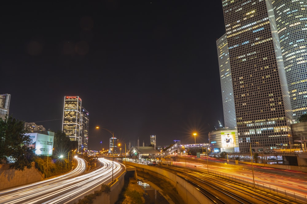 time-lapsed photography of vehicles on road beside buildings during nighttime