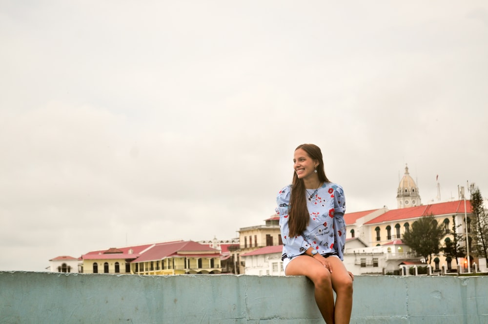 woman sitting on street wall