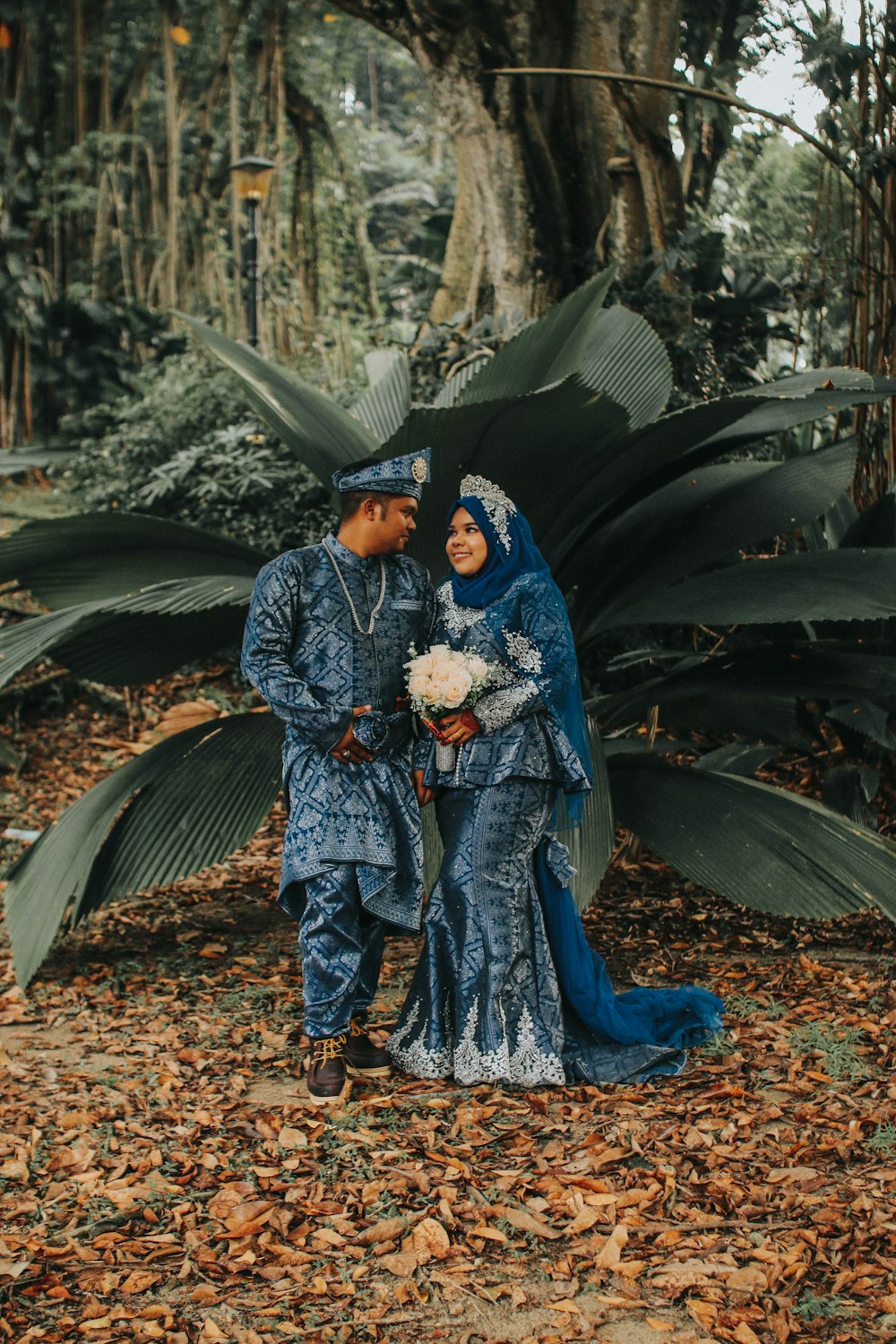 couple wearing matching thobe and dress in front of green plant during daytime