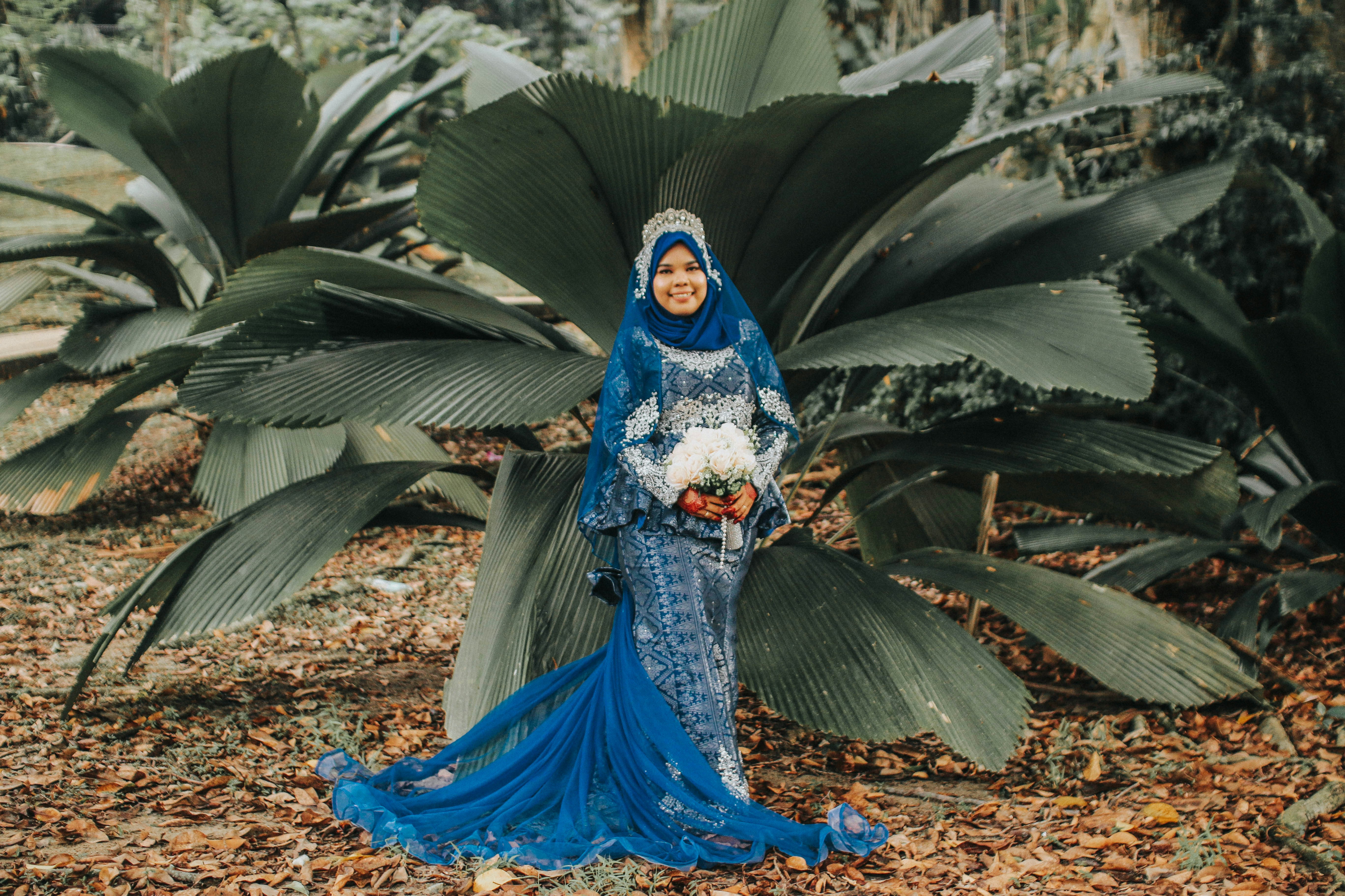 wanita mengenakan gaun bunga biru berdiri di samping tanaman