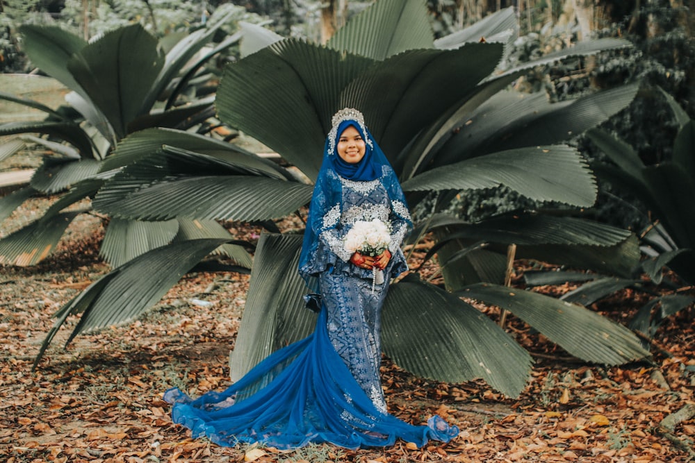 woman wearing blue floral dress standing beside plant