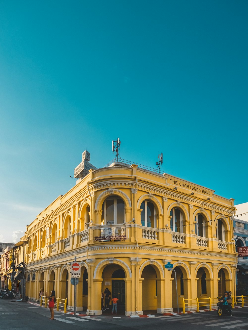 people beside yellow building during day