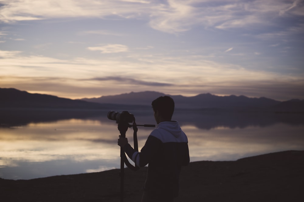 man holding tripod with camera near sea photo – Free Grey Image on Unsplash