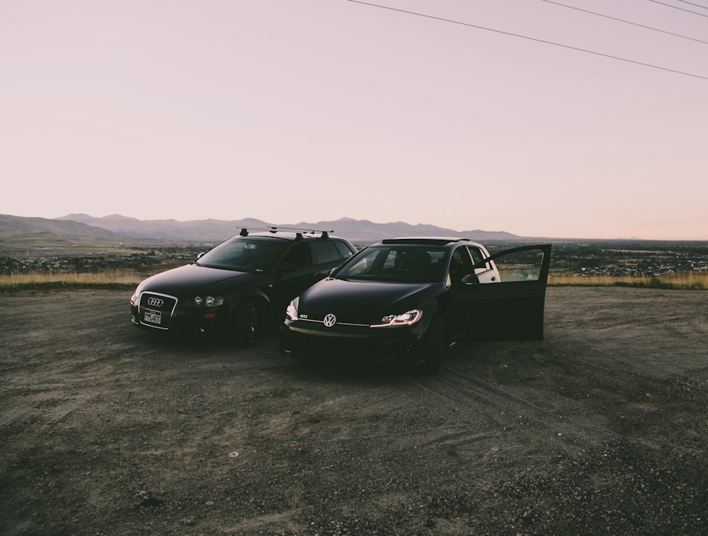 two black vehicles parked beside green grass