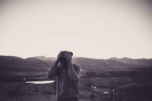 grayscale photo of man holding cap