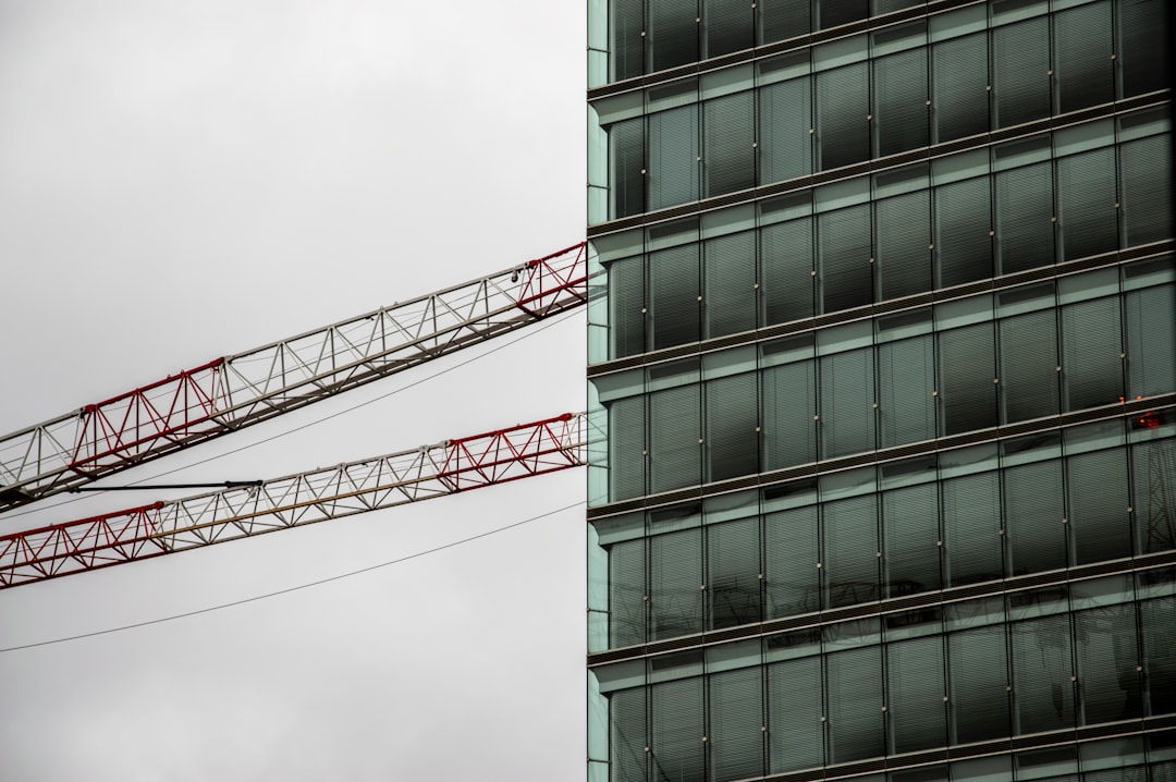 low-angle photography of red crane beside building during daytime