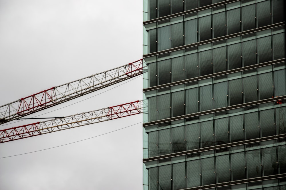 low-angle photography of red crane beside building during daytime