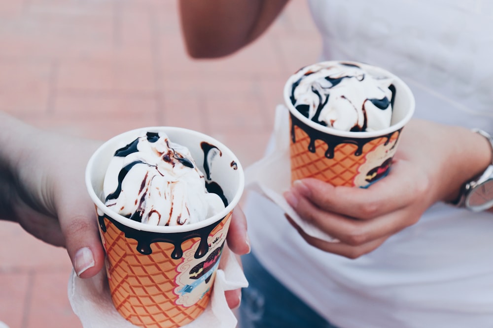 two person holding white icings with disposable cap