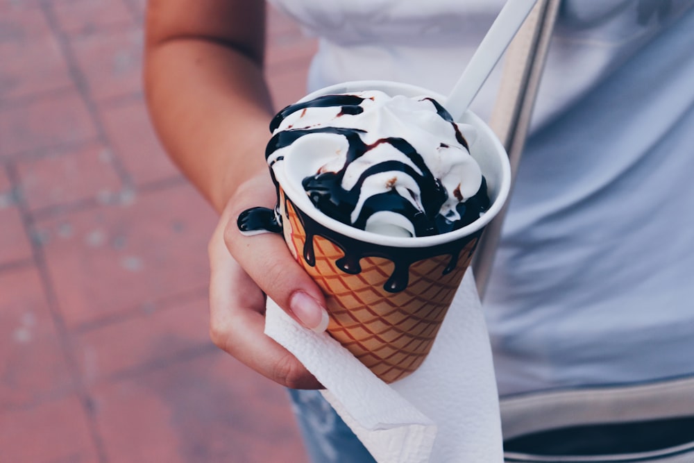 person holding brown and white ice cream cup